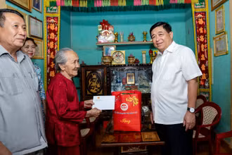 Bộ trưởng Kế hoạch và Đầu tư Nguyễn Chí Dũng (phải) thăm, tặng quà Mẹ Việt Nam Anh hùng Tạ Thị Phún ở huyện Vĩnh Linh, tỉnh Quảng Trị. (Ảnh: MINH SƠN)