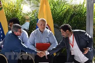 Trưởng đoàn đàm phán ELN Pablo Beltran (trái) và đại diện đoàn đàm phán của Chính phủ Ivan Cepeda (phải) trao đổi văn kiện thỏa thuận đạt được giữa 2 bên tại vòng đàm phán ở Caracas, Venezuela ngày 12/12/2022. (Ảnh: AFP/TTXVN)