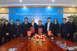 Đại biểu hải quan hai nước trao đổi biên bản ký kết tại hội nghị. (Ảnh: T.Bình) 