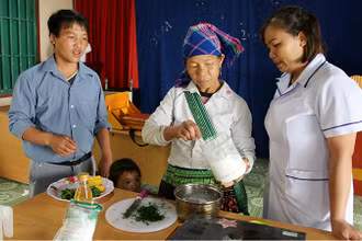 Cán bộ y tế hướng dẫn nấu bột cho người dân.