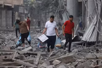 Người dân Palestine di chuyển qua đống đổ nát sau các cuộc không kích của Israel xuống Dải Gaza ngày 10/10/2023. (Ảnh: AFP/TTXVN)