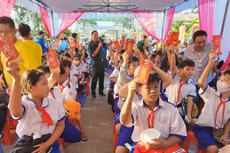 Học sinh biên giới tham dự chương trình chợ Tết yêu thương và nhận bao lì xì từ tay các bộ, chiến sĩ Đồn Biên phòng Sông Trăng, Long An trao. 