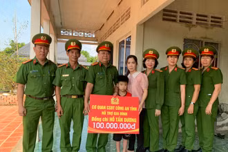 Lãnh đạo, chỉ huy khối điều tra trao tượng trưng số tiền 100 triệu đồng cho cháu Hồ Gia Bảo. (Ảnh: ĐOÀN DIỂU)