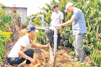 Cán bộ thuộc Dự án SACCR tại tỉnh Đắk Nông hướng dẫn người dân lắp đặt và sử dụng hệ thống tưới nước tiết kiệm cho vườn cà-phê.