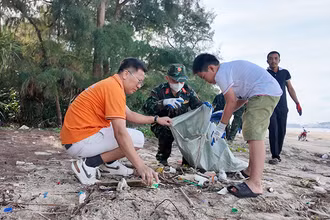 Người dân, học sinh cùng lực lượng chức năng tham gia dọn sạch bãi biển trên đảo Cô Tô. (Ảnh QUANG THỌ)