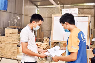 Vũ Anh Văn (bên trái) trao đổi với nhân viên về sản phẩm mới làm từ cây tre.