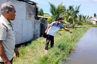 Ông Đặng Văn Đa (bên phải) chỉ nơi 2 cháu nội bị đuối nước tử vong.