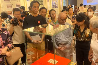 Khách tham quan thưởng lãm block tem kỷ niệm 70 năm Ngày sinh Chủ tịch Hồ Chí Minh có chữ ký của Người. (Ảnh: M.H)