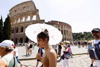 Khách du lịch đi bộ gần Đấu trường La Mã tại Rome trong đợt nắng nóng lan rộng khắp Italia, ngày 17/7/2023. (Ảnh: Reuters)