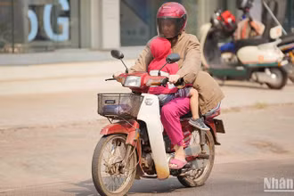 Người dân Lào tìm cách hạn chế nắng nóng khi tham gia giao thông. Ảnh: Hải Tiến