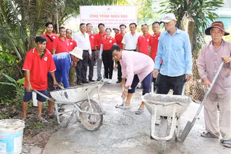 Thành viên Hội Chữ thập đỏ xã Đông Thạnh, thị xã Bình Minh (tỉnh Vĩnh Long) tham gia vá đường giao thông nông thôn. (Ảnh: BÁ DŨNG)