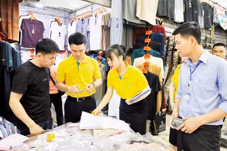 Nhân viên ngân hàng hướng dẫn hộ kinh doanh tại chợ Móng Cái thanh toán không dùng tiền mặt.