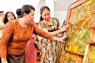 Nghệ nhân làng nghề sơn mài của Hà Nội giới thiệu sản phẩm tới Ðoàn công tác của Sở Công thương Viêng Chăn (Lào).
