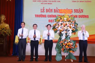 Nguyên Chủ tịch nước Nguyễn Minh Triết (bên phải) trao tặng lẵng hoa chúc mừng Trường Chính trị tỉnh Bình Dương đạt chuẩn mức 1. 