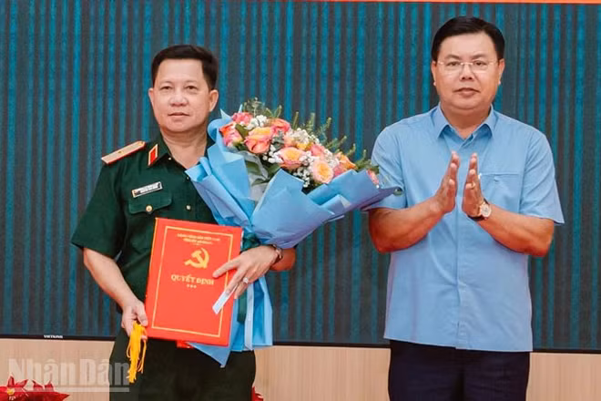 Đồng chí Nguyễn Tiến Hải, Ủy viên Trung ương Đảng, Bí thư Tỉnh ủy, Bí thư Đảng ủy Quân sự tỉnh An Giang trao quyết định, tặng hoa chúc mừng Thiếu tướng Nguyễn Văn Hùng. 