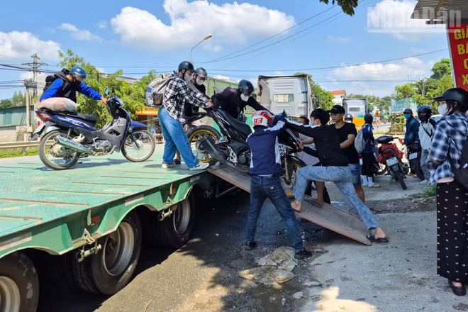 Các phương tiện xe máy được kéo lên xe đầu kéo để vượt qua các điểm ngập úng.
