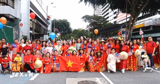 Cộng đồng người Việt tại Malaysia chụp ảnh lưu niệm cùng Thị trưởng Kuala Lumpur Maimunah Binti Mohd Sharif (hàng sau, giữa, khăn xanh) sau khi kết thúc diễu hành. (Ảnh: TTXVN)