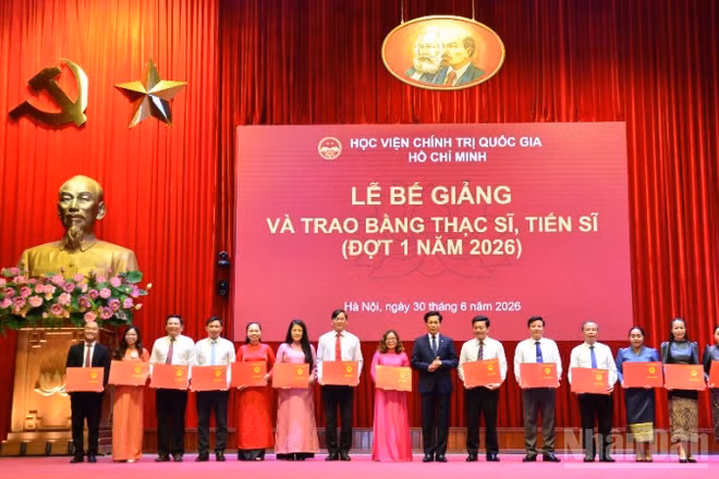 Đồng chí Hoàng Phúc Lâm, Phó Bí thư Đảng ủy, Phó Giám đốc Học viện Chính trị quốc gia Hồ Chí Minh trao bằng tiến sĩ cho các học viên. (Ảnh: PHẠM CƯỜNG)