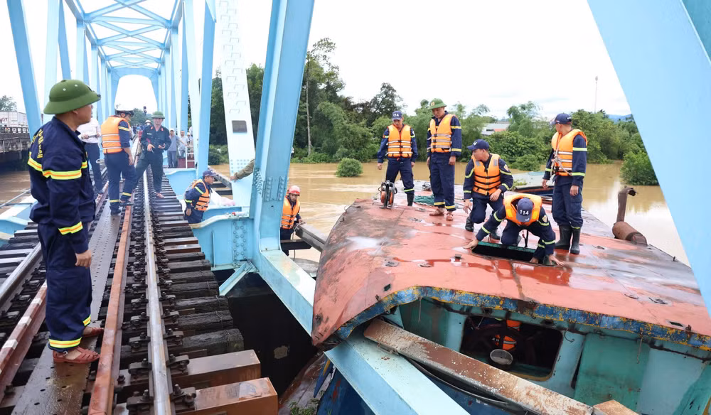 Lực lượng chức năng tiến hành cắt phần mái sà lan bị mắc kẹt với cầu đường sắt. (Ảnh: Công an tỉnh Quảng Trị)