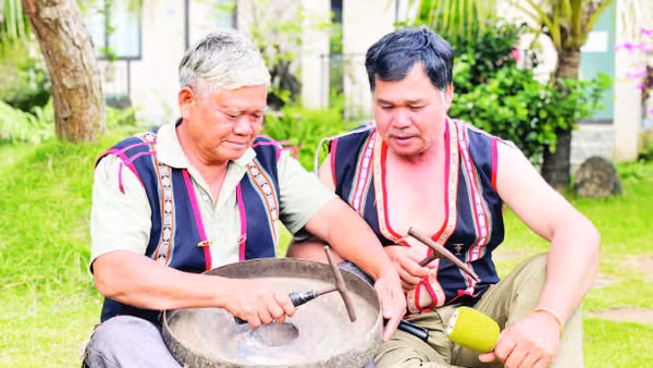 Nghệ nhân Ưu tú Đinh Dôch (bên trái) hướng dẫn kỹ thuật chỉnh chiêng cho học viên. (Ảnh LAM NGUYÊN)
