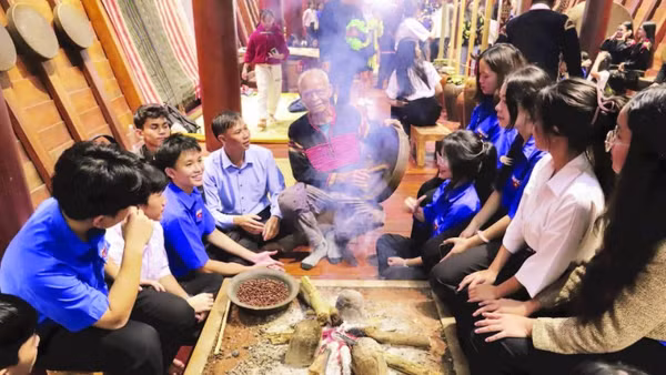 Già làng người Ê Đê ngồi kể chuyện về văn hóa cồng chiêng cho các cháu học sinh bên bếp lửa trong ngôi nhà dài truyền thống.