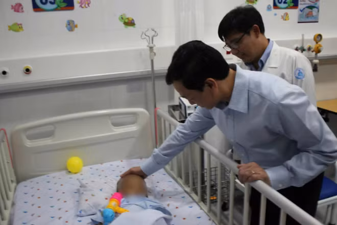 Thứ trưởng Bộ Y tế Nguyễn Tri Thức thăm cháu bé bị bạo hành tại Bệnh viện Nhi đồng 1, Thành phố Hồ Chí Minh. (Ảnh: ĐỖ BÁ)