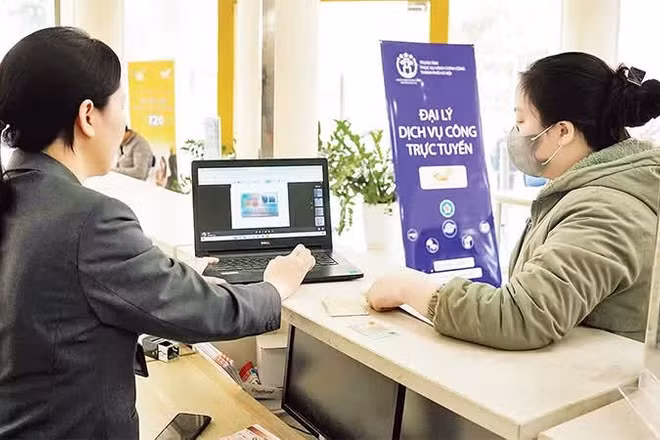 Người dân được nhân viên hướng dẫn làm thủ tục hành chính tại các đại lý dịch vụ công trực tuyến của thành phố Hà Nội. (Ảnh: NGUYÊN TRANG)