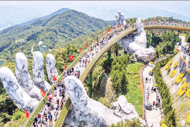 Du khách thưởng lãm khung cảnh công trình "Cầu Vàng" rợp bóng cờ đỏ sao vàng. (Ảnh: PHAN HẢI TÙNG LÂM)