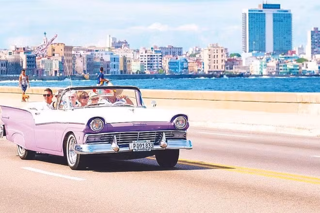 Du khách đi xe cổ ngắm thủ đô La Habana. (Ảnh: KIMKIM.COM)