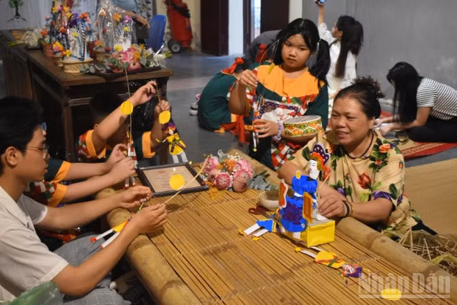 Nghệ nhân Nguyễn Thị Tuyến giới thiệu đồ chơi Tiến sĩ giấy với các bạn trẻ.