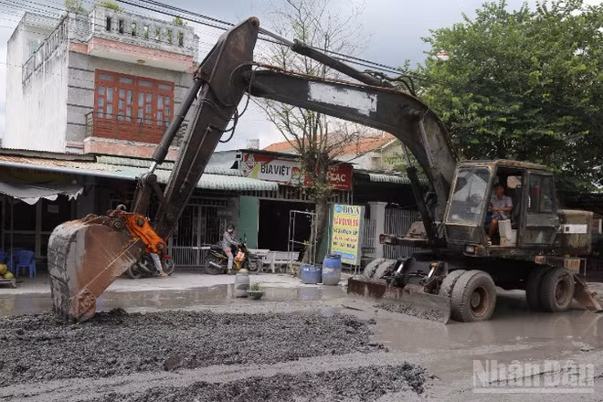 Đơn vị thi công dùng xe múc sửa chữa nền đường Bưng Môn.