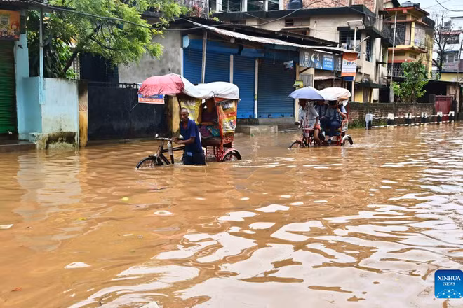 Người dân di chuyển qua vùng nước lũ sau đợt mưa lớn vào năm ngoái thành phố Guwahati, bang Assam, đông bắc Ấn Độ. (Ảnh: THX)