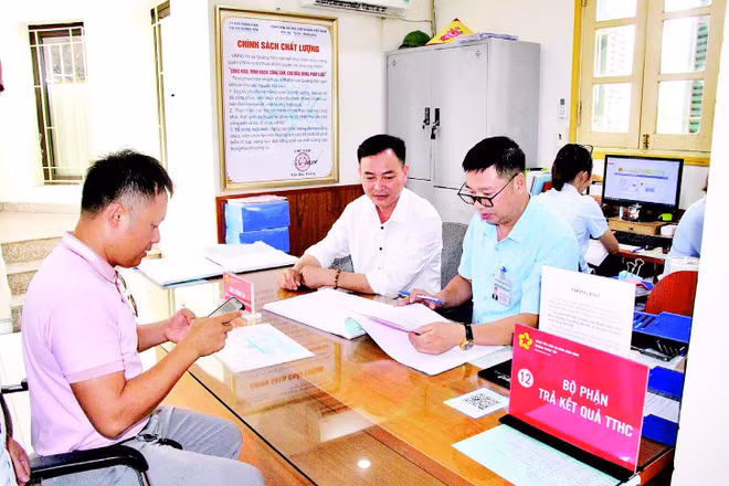 Cán bộ Trung tâm Phục vụ hành chính công phường Quảng Yên (tỉnh Quảng Ninh) hỗ trợ người dân làm thủ tục hành chính. (Ảnh QUANG THỌ)