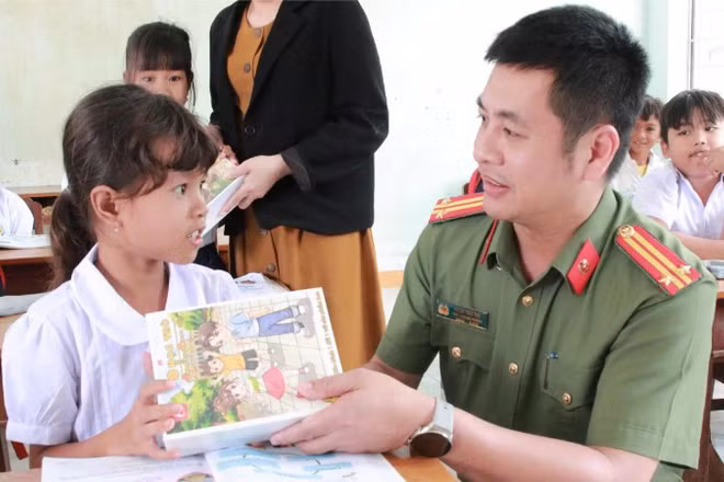 Cán bộ Công an tỉnh Đắk Lắk trao tặng sách vở cho học sinh vùng lũ tại xã Phú Mỡ sau khi các em trở lại trường học.