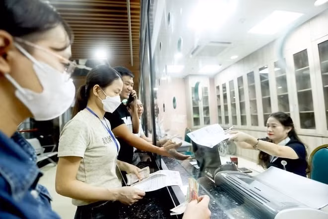 Người dân nộp tiền khám sức khỏe tại Bệnh viện Bạch Mai, Hà Nội. (Ảnh NGUYỄN KHÁNH)