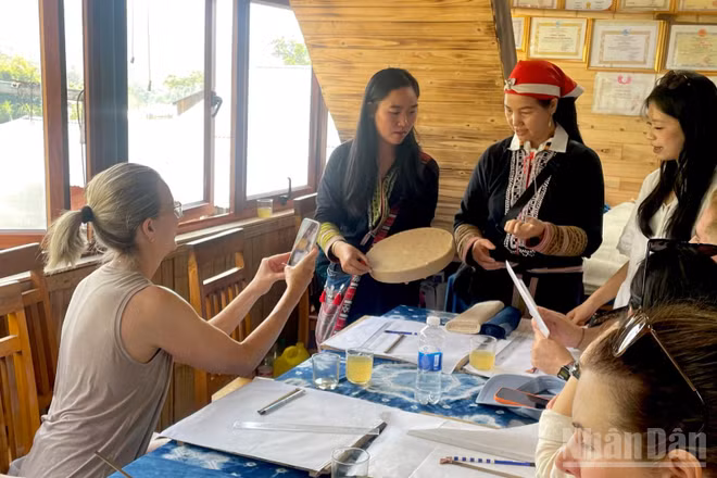 Du khách tìm hiểu kỹ thuật vẽ hoa văn bằng sáp ong và nhuộm chàm tại bản Tả Van. (Ảnh: NGỌC LIÊN)