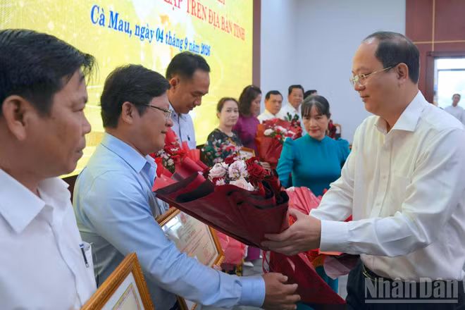 Đồng chí Nguyễn Hồ Hải, Ủy viên Trung ương Đảng, Bí thư Tỉnh ủy Cà Mau (bên phải) tặng hoa và Bằng khen của Chủ tịch tỉnh cho các tập thể, cá nhân có thành tích xuất sắc trong sắp xếp trường, lớp. (Ảnh: HỮU TÙNG)