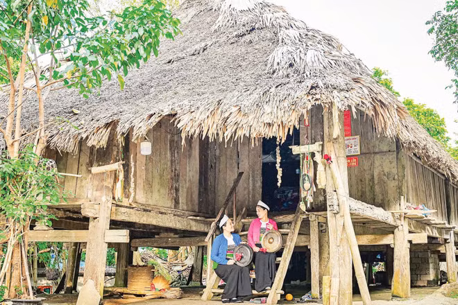 Phụ nữ Mường ở Giang Mỗ luyện tập biểu diễn chiêng Mường bên nhà sàn cổ. (Ảnh: BẢO LONG)