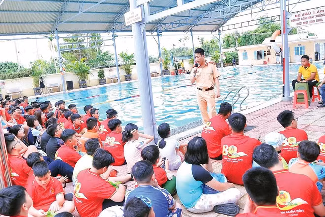 Cán bộ công an tuyên truyền về kỹ năng phòng, chống đuối nước cho trẻ em tại khu vực bể bơi.