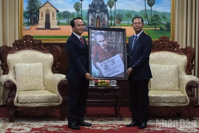 Phó Bí thư Thường trực Thành ủy Đà Nẵng Nguyễn Đình Vĩnh trao tặng bức ảnh Bác Hồ đọc Báo Nhân Dân cho lãnh đạo tỉnh Savannakhet. (Ảnh: ANH ĐÀO)