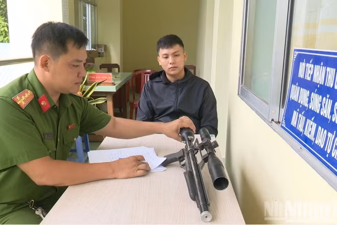 Anh Phạm Minh Sang giao nộp khẩu súng quân dụng nhặt được cho Công an xã Chợ Gạo. (Ảnh: LÊ HOÀI)