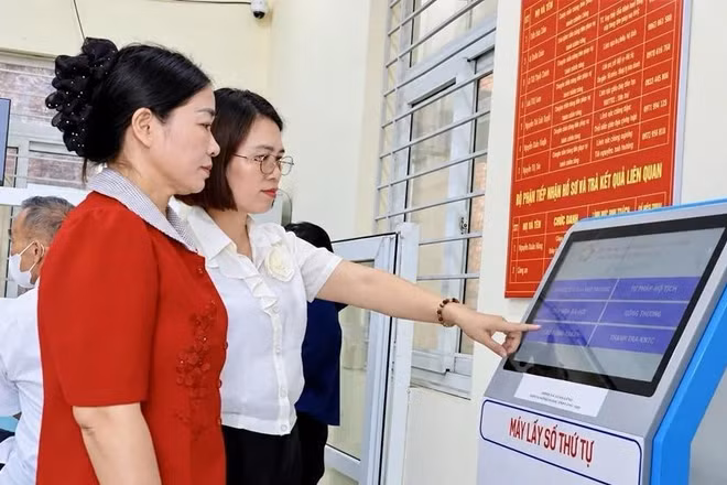 Cán bộ Trung tâm Phục vụ hành chính công xã Xuân Lãng hướng dẫn người dân sử dụng thiết bị lấy số thứ tự.