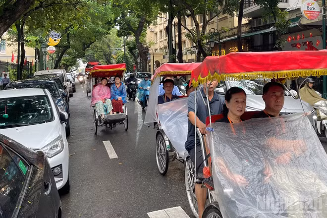 Du khách nước ngoài trên phố Tràng Thi (Hà Nội) ngày mưa. (Ảnh minh họa: Đ.T)