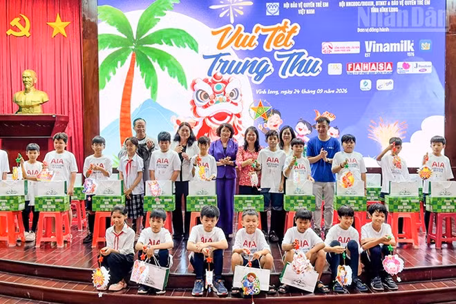 Đồng chí Đặng Thị Ngọc Thịnh, nguyên Ủy viên Trung ương Đảng, nguyên Phó Chủ tịch nước cùng nhà tài trợ trao quà cho các em thiếu nhi. (Ảnh: BÁ DŨNG)