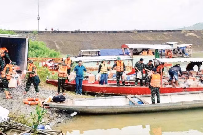 Các lực lượng chức năng xã Trà Đốc xếp lương thực, nhu yếu phẩm lên thuyền để vượt sông Tranh vào tiếp tế cho người dân bị cô lập.