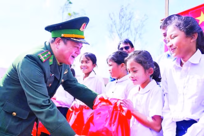Cán bộ Đồn Biên phòng Hướng Lập trao quà tặng học sinh hai bên biên giới.