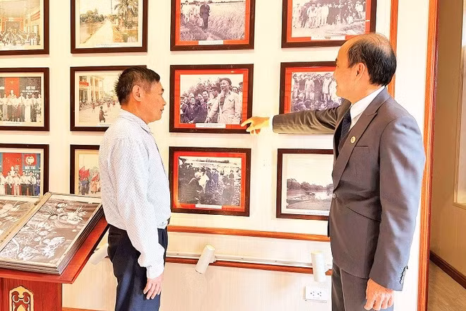 Ông Phùng Văn Tiệp (bên phải), Trưởng phòng Văn hóa-Xã hội xã Dân Hòa giới thiệu cho khách tham quan các hình ảnh về Chủ tịch Hồ Chí Minh tại Nhà lưu niệm Chủ tịch Hồ Chí Minh tại xã Dân Hòa.