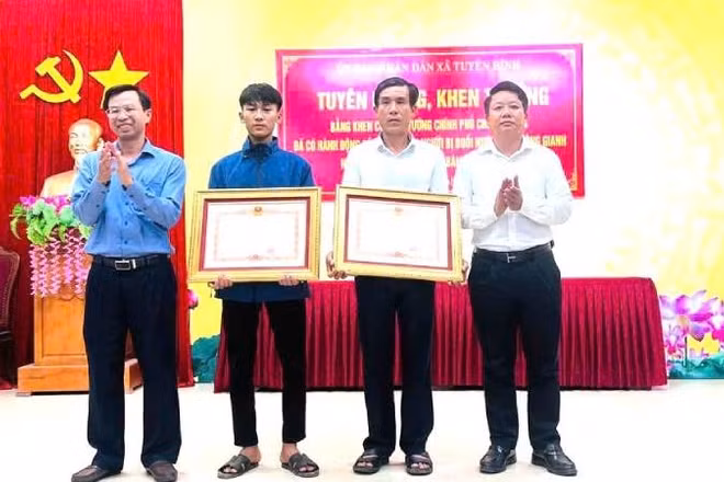 Bố con ông Cao Hữu Tình và em Cao Hoàng Ân Đức nhận Bằng khen của Thủ tướng Chính phủ vì đã có hành động dũng cảm cứu người đuối nước trên sông Gianh.