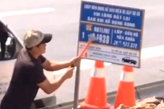 Đối tượng sử dụng dụng cụ cạo sơn để cạo thông tin các số điện thoại hotline và số điện thoại cứu hộ, sửa chữa phương tiện được dán trên biển báo thông tin cứu hộ bị ghi lại hình ảnh. 