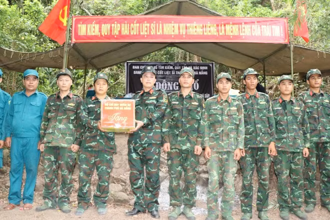 Đại tá Trần Hữu Ích trao quà, động viên cán bộ, chiến sĩ Đội tìm kiếm, quy tập hài cốt liệt sĩ của Bộ Chỉ huy Quân sự thành phố đang thực hiện nhiệm vụ tại hiện trường.
